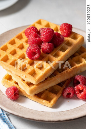 Breakfast waffles with berries in plate served with cup of tea. Breakfast waffles with berries in plate served with cup of tea. 100859228