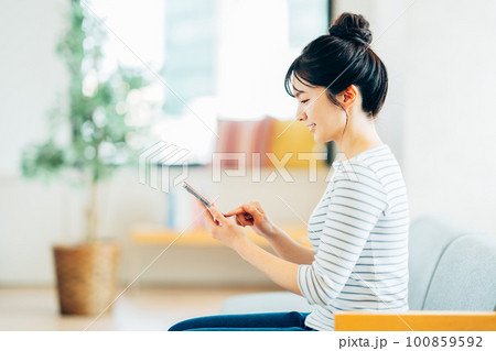 リビングでスマホを見る若い女性。 リビングでスマホを見る若い女性。 100859592
