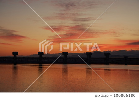 赤く朝焼けした空と映り込む川・春・230301am 100866180
