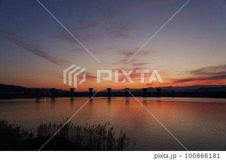 赤く朝焼けした空と映り込む川・春・230301am 100866181