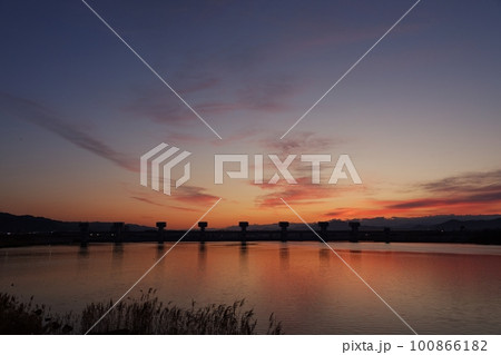 赤く朝焼けした空と映り込む川・春・230301am 100866182