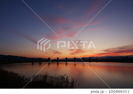 赤く朝焼けした空と映り込む川・春・230301am 100866351