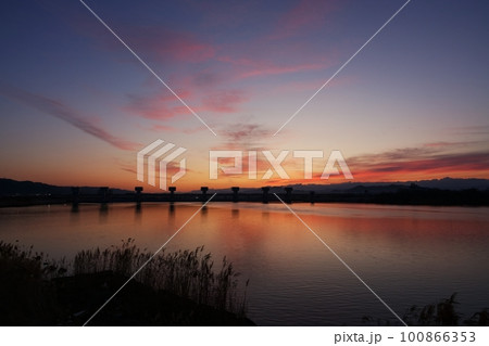 赤く朝焼けした空と映り込む川・春・230301am 100866353