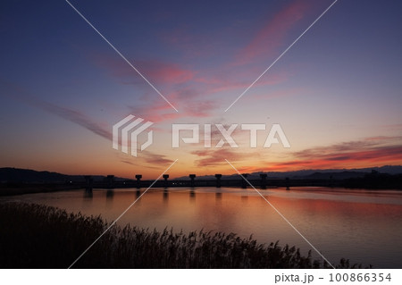 赤く朝焼けした空と映り込む川・春・230301am 100866354