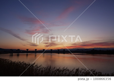 赤く朝焼けした空と映り込む川・春・230301am 100866356