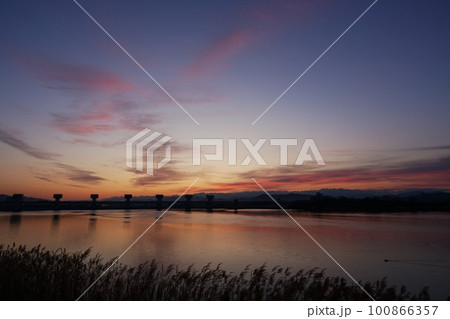 赤く朝焼けした空と映り込む川・春・230301am 100866357