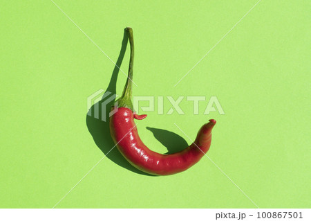 red hot pepper on a green background with a hard shadow red hot pepper on a green background with a hard shadow 100867501