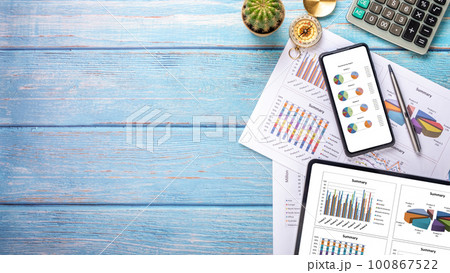 Tablet and smart phone with charts and reports on office desk workplace. Top view flat lay Tablet and smart phone with charts and reports on office desk workplace. Top view flat lay 100867522
