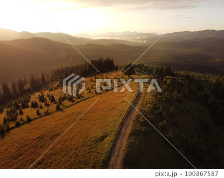Aerial view of beautiful mountain Carpathians, Ukraine in sunlight. Drone filmed an landscape with coniferous and beech forests, around a winding serpentine road, copter aerial photo 100867587