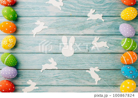 Easter Day Concept. Top view holiday banner background web design white colorful easter eggs and paper bunny rabbit on blue wood background with copy space, celebration greeting, overhead, template 100867824
