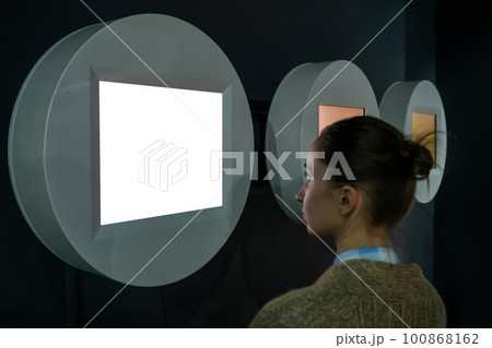 Woman looking at blank white display wall at exhibition - white screen concept 100868162