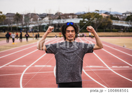 陸上競技のトラックでガッツポーズをする男性ランナー 100868501