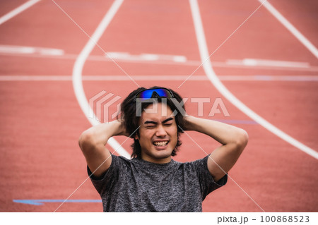 陸上競技のトラックに座り込む男性ランナー 陸上競技のトラックに座り込む男性ランナー 100868523