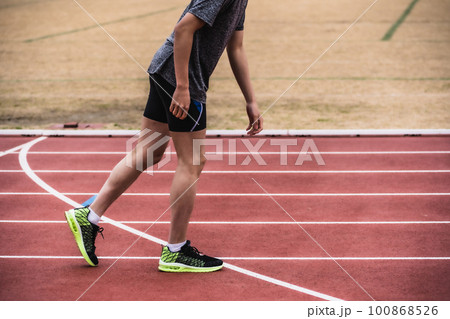 陸上競技のトラックで足を引きずるように歩く男性ランナー 100868526