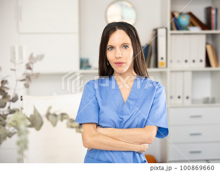 Woman doctor standing inside office, looking at camera 100869660