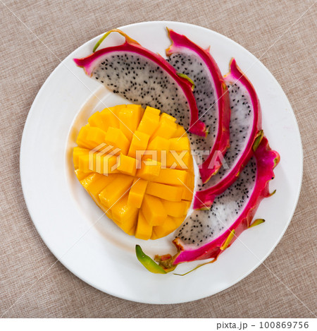 Plate of slices of ripe sweet and juicy mango and pitaya Plate of slices of ripe sweet and juicy mango and pitaya 100869756