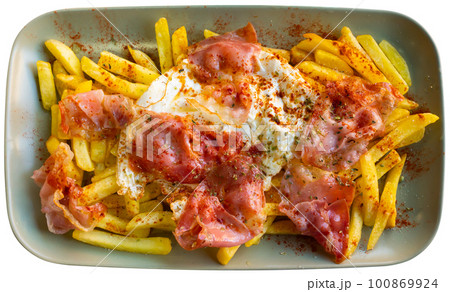 Fried eggs cooked spanish style with potatoes and slices of hamon with sliced bread glass of wine and cutlery 100869924