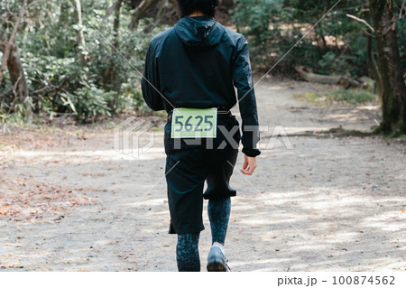 トレイルランでゼッケンをつけた男性ランナーの後ろ姿 100874562