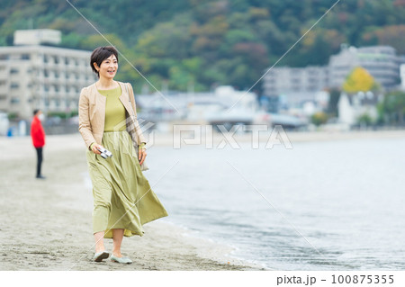カメラを持って海辺を歩くミドル女性 カメラを持って海辺を歩くミドル女性 100875355
