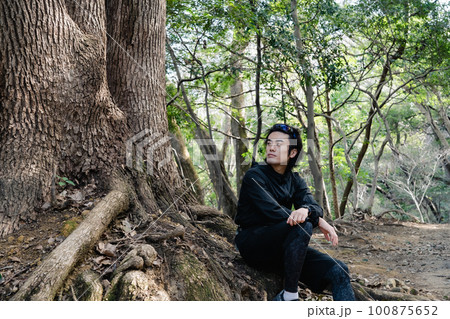 大きな木の根元に座る男性ランナー 100875652