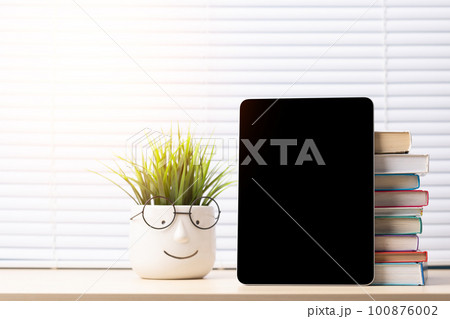 Tablet and stack of books Tablet and stack of books 100876002