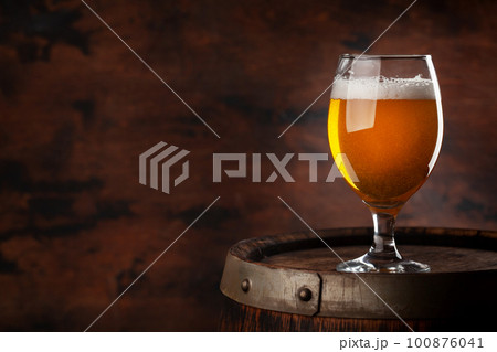 Beer glass on wooden barrel Beer glass on wooden barrel 100876041