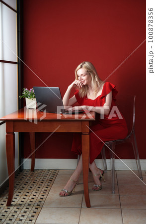 Young adult woman sitting at the table and working on laptop Young adult woman sitting at the table and working on laptop 100878356