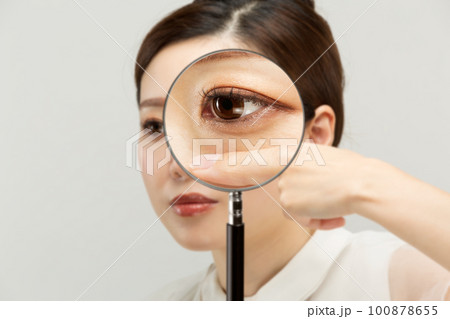 女性の下瞼をルーペで拡大している。 100878655