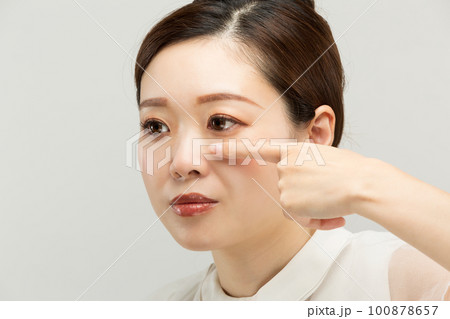 女性は下瞼をおさえている。 100878657