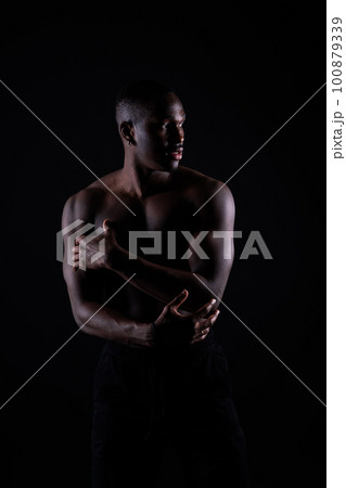 One young african muscular build man standing topless silhouette isolated on black background 100879339