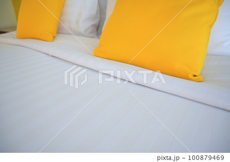 yellow pillow on white bed, interior design 100879469