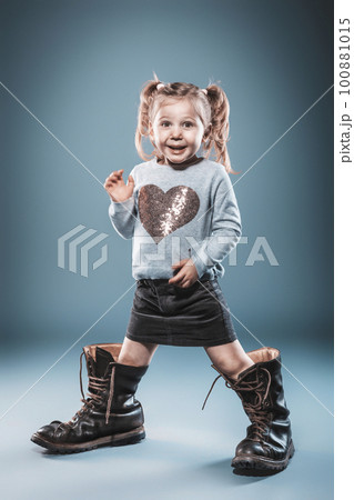 blonde girl plays with big boots. blonde girl plays with big boots. 100881015