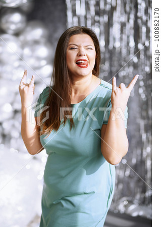 Happy plus size woman showing rock and roll hand gesture Happy plus size woman showing rock and roll hand gesture 100882170