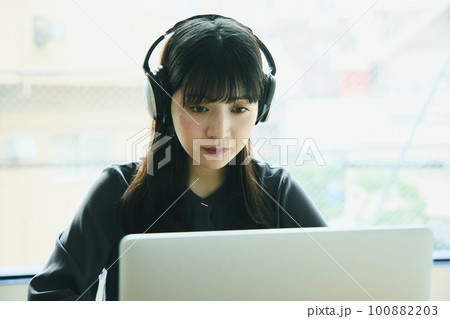 オフィスでノートパソコンを使っている若い女性 100882203