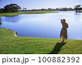 Retro styled woman standing at the lake 100882392