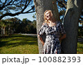 Beautiful woman leaning onto the oak tree 100882393