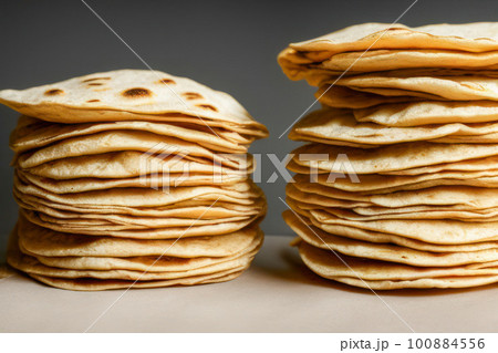 Stack of homemade wheat flour tortillas for making takos on grey table background. Mexican food concept. Stack of homemade wheat flour tortillas for making takos on grey table background. Mexican food concept. 100884556