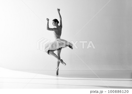 Monochrome. Ballerina wearing tutu poses in motion showing ballet elements while standing on pointe shoes over white backgrounds 100886120