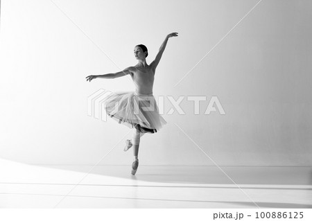 Monochrome. Young graceful ballerina posing in studio and demonstrating elegant movement Monochrome. Young graceful ballerina posing in studio and demonstrating elegant movement 100886125