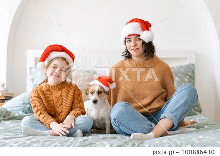 Happy woman with daughter in santa hat enjoying her cute dog jack russell. Happy woman with daughter in santa hat enjoying her cute dog jack russell. 100886430