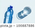 Bottled water. A bottle of mineral water and glass of water with hard shadows on blue background. Flat lay Top view 100887886