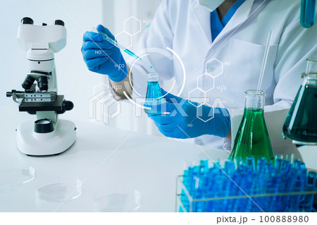 Scientist mixing chemical liquids in the chemistry lab. Researcher working in the chemical laboratory. 100888980