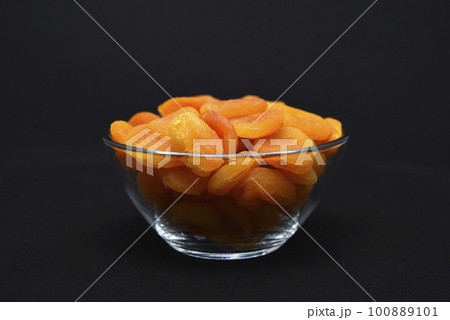 Juicy dried apricots in a glass bowl. Dried apricot fruit halves without a stone. 100889101