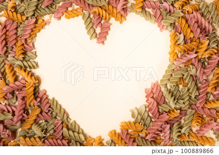Rice vegetable pasta on a white background, laid out in the shape of a heart, a place for text. Rice vegetable pasta on a white background, laid out in the shape of a heart, a place for text. 100889866