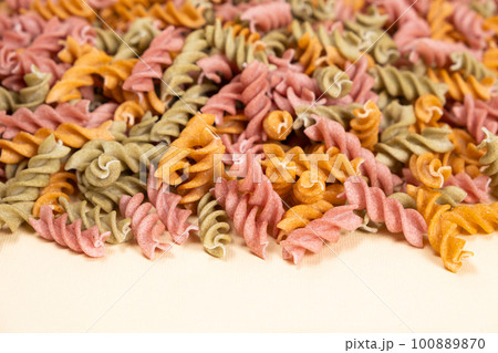 Rice vegetable pasta in the form of spirals on a white background. Healthy rice pasta with tomatoes, selenera, carrots and beets Rice vegetable pasta in the form of spirals on a white background. Healthy rice pasta with tomatoes, selenera, carrots and beets 100889870