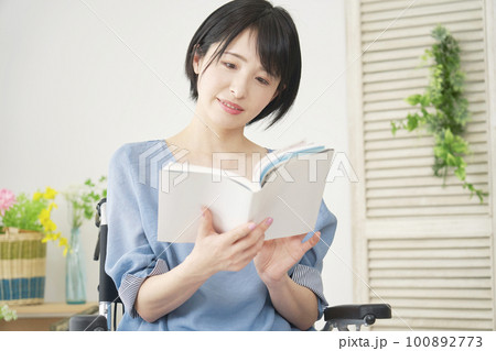 リビングで読書する車椅子に乗った女性 100892773