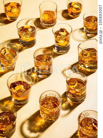 Whiskey and bourbon in luxury glasses with ice cubes on golden background. 100893007