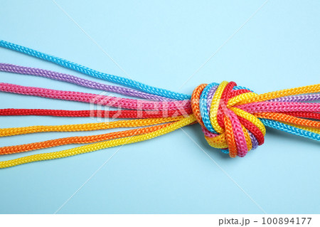 Colorful ropes tied together on light blue background, top view. Unity concept Colorful ropes tied together on light blue background, top view. Unity concept 100894177