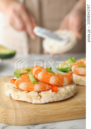 Puffed rice cake with shrimps and avocado on wooden board, closeup 100894297