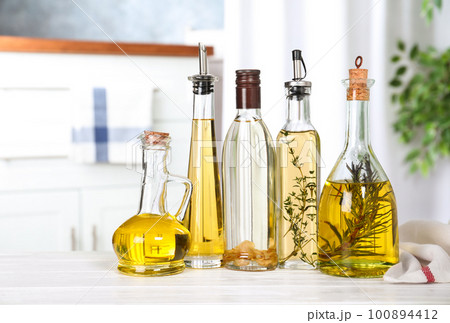 Different sorts of cooking oil in bottles on table indoors Different sorts of cooking oil in bottles on table indoors 100894412